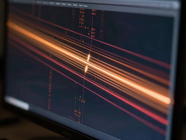 Extreme close-up of a generative AI interface on a dark monitor, amber and crimson data streams flowing across the screen, side-lit by a single low-temperature LED source, reflective glass surface catching the glow, editorial framing