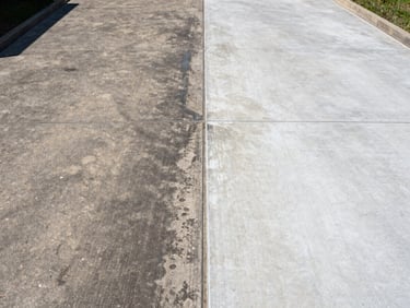 Before-and-after split of a concrete driveway, left half dark with grime, right half freshly pressure-washed to pale clean concrete, bright daylight, direct overhead angle