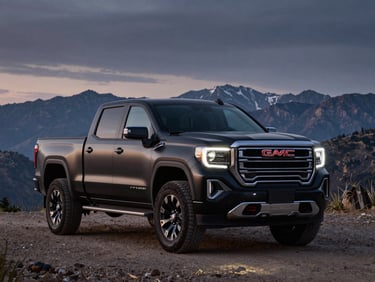 Wide shot of a brand-new matte black GMC Sierra 1500 AT4X in a rugged mountain landscape at dusk, headlights on, dramatic sky behind, environmental product photography