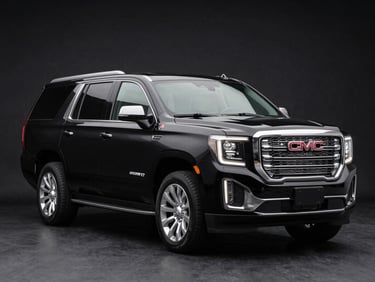Studio-quality hero shot of a brand-new GMC Yukon Denali XL in onyx black, shot from a low three-quarter angle, chrome trim highlighted by studio spotlights, clean dark background