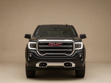 Head-on studio shot of a brand-new GMC Sierra truck, matte black paint, chrome badge centered, dramatic low-key lighting with a crisp parchment-toned background, wide environmental framing with negative space on both sides