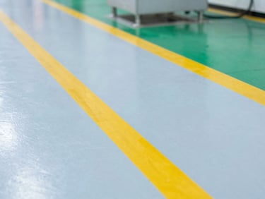 Crisp industrial photography of a clean factory floor with yellow safety lines, bright overhead lighting, sharp focus, 35mm lens
