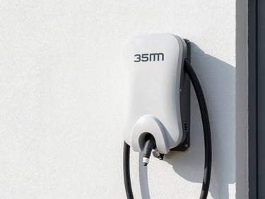 Crisp technical photography of a modern EV charging station (wallbox) installed at a home, clean wiring, bright natural daylight, sharp focus.