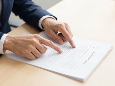 Close-up of a legal expert's hands pointing to a section of a legal document related to trademark registration, on a clean desk, warm gold accents, shallow depth of field.
