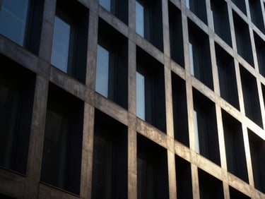 Architectural close-up of a modern steel and concrete facade, dramatic low-key side-lighting, deep shadows, 35mm.