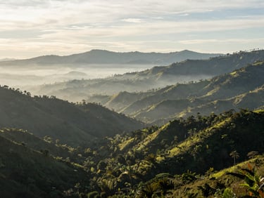 Wide panoramic shot of Coclé highlands under soft morning mist, lush green mountains stretching into the distance, serene and quiet atmosphere
