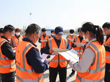 Active community volunteers in bright orange high-visibility vests coordinating with maps and handheld radios during a daytime training exercise, wide environmental shot