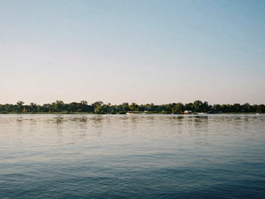 A quiet view of the Savannah River in Augusta at daylight, calm water reflecting the soft sky, wide environmental landscape, 35mm