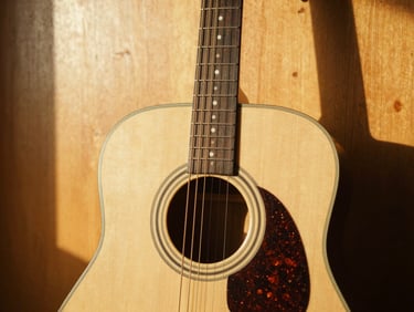A close-up of an acoustic guitar leaning against a warm wood wall, golden hour sunlight casting soft shadows, 35mm photography
