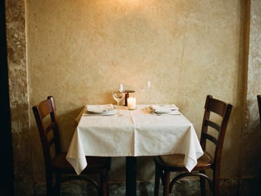 Intimate restaurant setting in Lisbon with two empty chairs, soft candlelight on a table set for two, warm editorial photography, authentic Portuguese atmosphere, 35mm film aesthetic