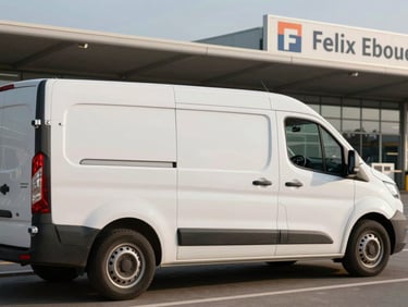 Exterior side view of a clean white shuttle van parked at Felix Eboue airport departures drop-off zone, late afternoon light, airport signage partially visible in background, no passengers