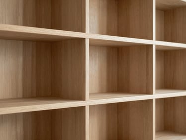 Detail shot of custom wooden millwork and shelving in a minimalist study, soft shadows, warm ambient lighting highlighting wood grain