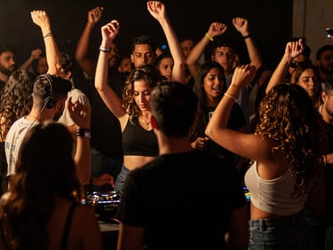 Escenario con luces inteligentes y DJ profesional animando una fiesta de quince años, con personas bailando en la penumbra, estilo cinematográfico.