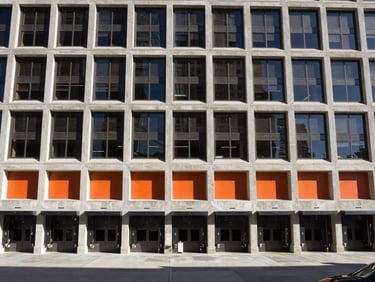Wide-angle architectural lens view of the Rossi Group Denver headquarters exterior, showing active loading bays and structured concrete design under high-contrast daylight