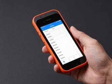 Hands holding a handheld Android scanner displaying a clean logistics inventory grid, sharp technical focus