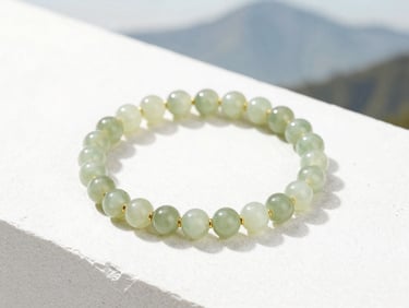 Elegant gold bracelet with small, polished jade beads, soft natural mountain daylight, clean white stone backdrop.