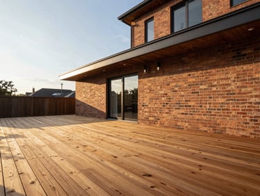 Wide-angle architectural shot of a modern wood deck integrated with a brick home, clean lines, late afternoon sun.
