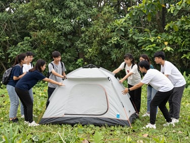 Students collaboratively pitching a tent in a lush green forest clearing, natural daylight, candid action, 35mm lens