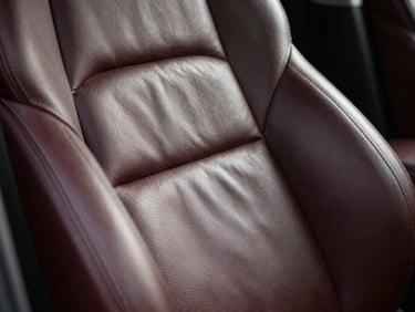 Close-up of a car's leather seat being cleaned and conditioned, showing a rich, restored texture, soft natural light