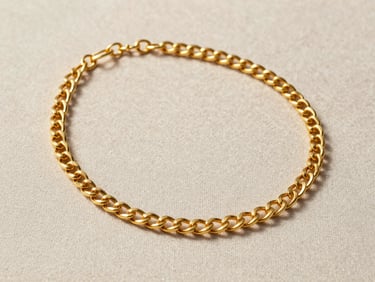 A finished 22-karat gold necklace laid flat on a neutral linen surface under warm indirect daylight, showing the weight and texture of the metal links in sharp focus, medium shot isolating the piece