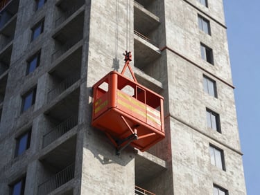 Heavy-duty passenger hoist structure attached to the side of a tall residential concrete tower under construction