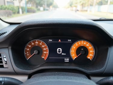 Clean close-up of a modern car dashboard with a digital speedometer showing low mileage, bright natural daylight, cool slate and warm orange tones, sharp focus, 35mm