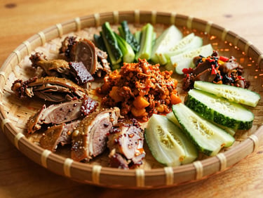Traditional Javanese family platter featuring duck, chicken, vegetables, and sambal on a woven bamboo tray