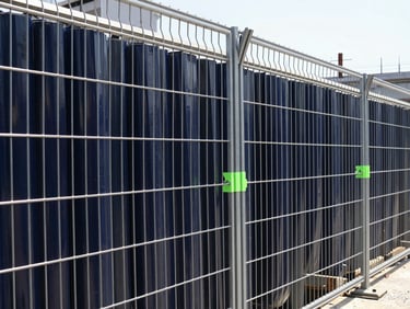 Heavy-duty steel fencing enclosing an urban subway construction site during the day, clean steel texture, professional setup