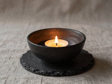 Moody editorial photography of steam gently rising from a dark slate ceramic bowl, low-key warm candlelight, deep soft shadows, linen texture background, 35mm lens