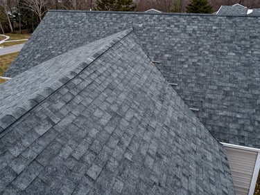 Overhead wide shot of a finished asphalt shingle roof on a DC-area residential home, overcast natural light, full roof geometry visible from above, clean ridge and valley lines, no people