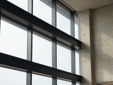 Architectural detail of a modern office building interior, clean lines, concrete and steel, soft natural light filtering through glass.