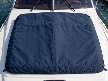 Overhead view of a navy bimini cover fitted over a yacht cockpit at a marina, stitching lines sharp in flat coastal daylight, ropes and cleats visible at frame edges