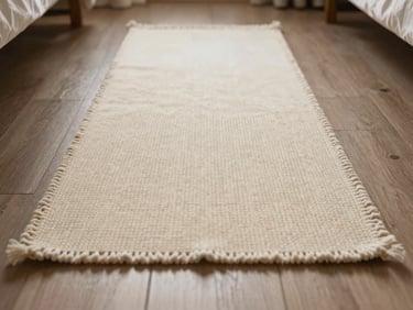 Low-angle floor-level shot of a soft cream wool runner in a sunlit bedroom, casting soft shadows across the deep weave, 35mm.