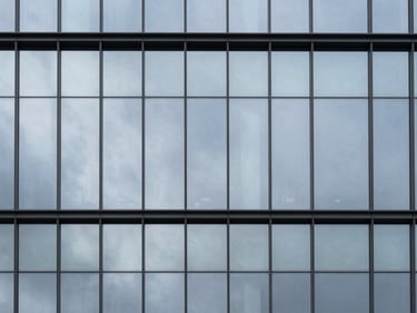 Minimalist corporate glass facade reflecting a cold silver sky, sharp focus, architectural photography, 35mm