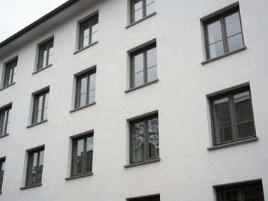 Exterior of a mid-rise residential building showing freshly painted facade surface and window seals, overcast natural light, no people, clean architectural framing from street level