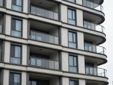 Close-up of a residential condominium building exterior facade showing rendered finish and window framing detail, overcast natural daylight, no people, flat environmental framing