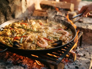 Close-up of bubbling paella on open orange wood fire, glowing embers, warm editorial photography, 35mm