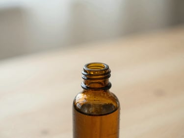 Close-up of an amber glass dropper bottle on a light wood surface, soft diffused morning daylight, shallow depth of field, muted sage and cream tones.