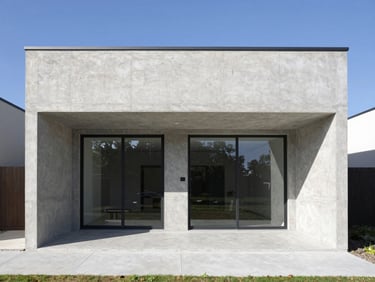 Straight-on architectural shot of a modern single-family concrete house, sharp shadows, bright daylight