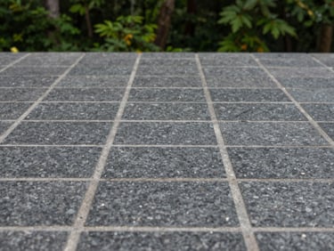 Close-up of perfectly aligned dark granite paving stones with clean grey joints under soft overcast daylight, shallow depth of field, 35mm