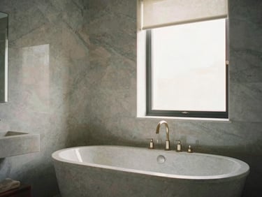 Architectural-digest-level shot of a master bathroom sanctuary, freestanding stone bathtub, flawless grey marble wall joints, soft window light.
