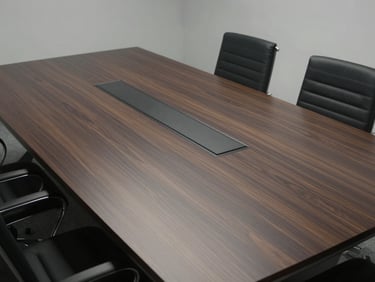 High-angle view of a clean, minimalist corporate boardroom with a long dark oak table, cool diffused light