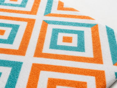 Close-up of a bath mat with a unique geometric pattern in vibrant orange and white, showing rich textile texture, sharp details, 35mm