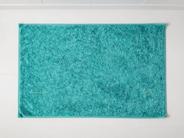 Top-down flat lay of a soft, textured teal bath mat on a clean white bathroom floor, bright lighting, 35mm