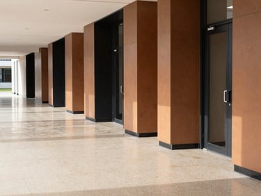 Clean architectural shot of an empty modern school hallway with highly polished light beige terrazzo floors, bright natural daylight, structured and pristine.