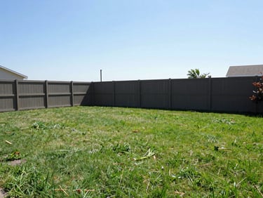 After: The exact same backyard, cleared of all debris, swept clean, showing open green grass and a clean fence line under bright daylight.