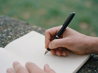 Close-up of hands writing on a legal pad with a fountain pen, soft British daylight, muted forest green and stone tones, 35mm film grain.