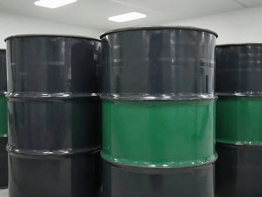 Close-up of sealed industrial steel drums stacked in a clean, organized warehouse, overhead white lighting