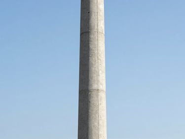 A sharp industrial shot of a concrete utility pole standing tall against a clear sky, high-contrast, technical framing
