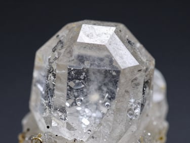 Macro shot of a perfectly formed quartz crystal showing hexagonal habit, diffused high-CRI lighting, deep charcoal background, sharp focus on crystal textures.